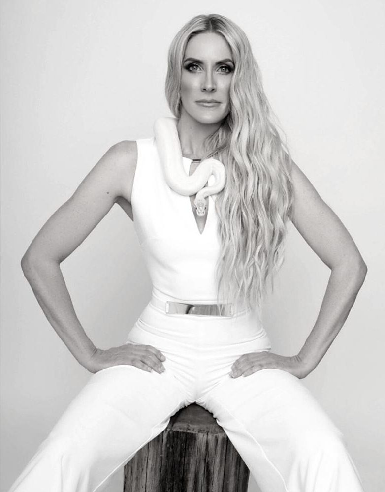 Tara Delle Chiaie poses in a white outfit with an albino python around her neck to model for the gravity form of the homepage with special offer.