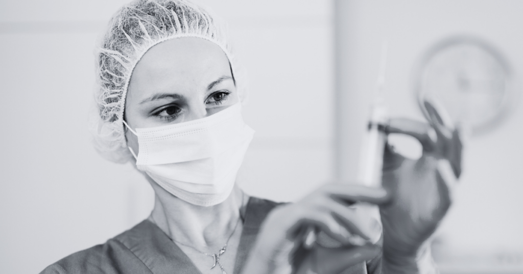 a nurse having a syringe and wearing a mask