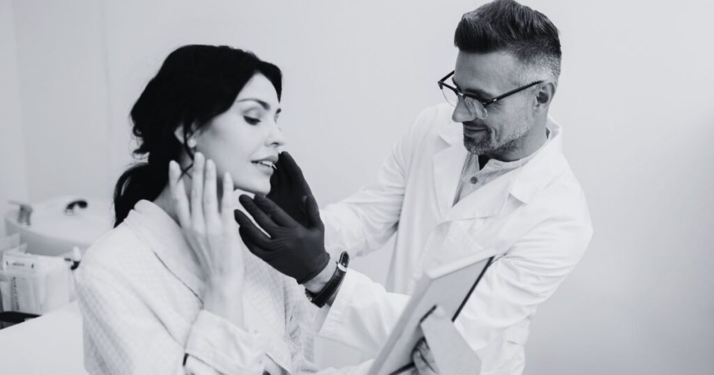 Aesthetic provider performing a full-face facial assessment during a patient consultation.