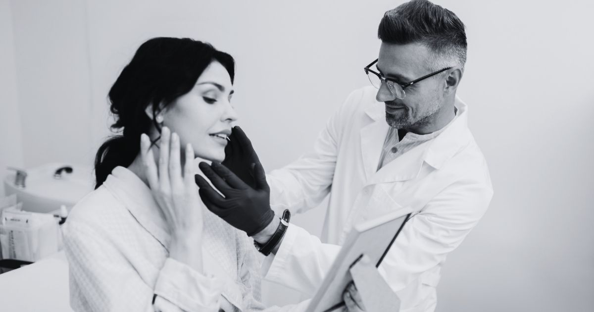Aesthetic provider performing a full-face facial assessment during a patient consultation.