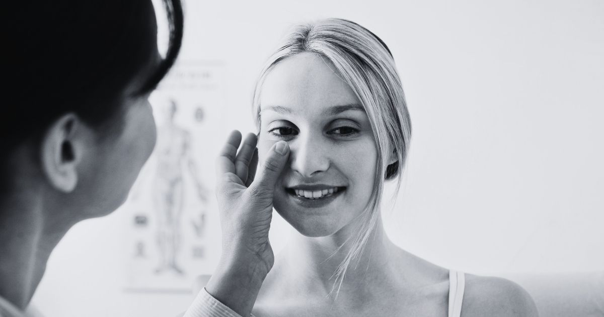 Aesthetic professional examining a woman’s facial anatomy.